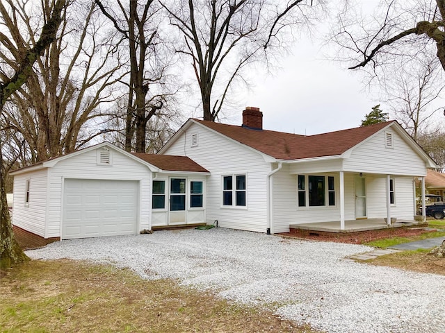 view of front facade with an attached garage, a porch, roof with shingles, a chimney, and driveway