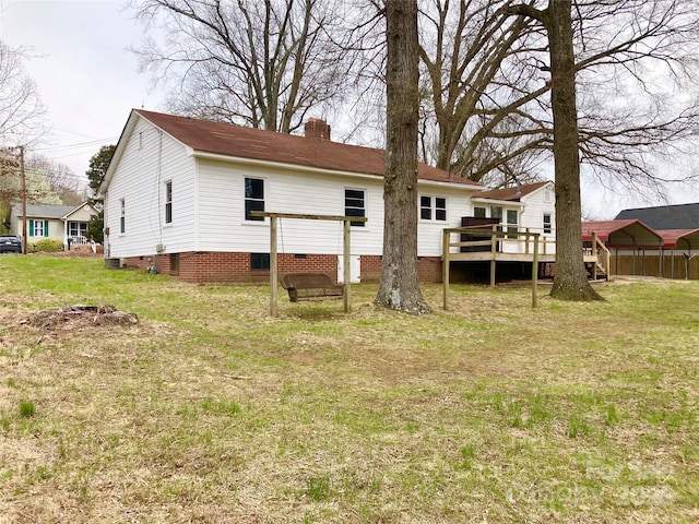 rear view of property featuring fence, a wooden deck, a chimney, crawl space, and a lawn