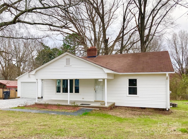 view of front of house with gravel driveway, a front lawn, a porch, a chimney, and a garage