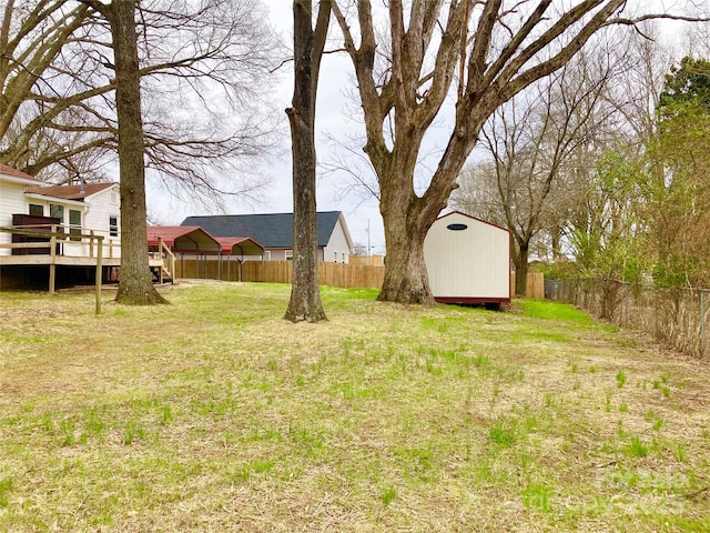 view of yard featuring a wooden deck, an outbuilding, a fenced backyard, and a shed