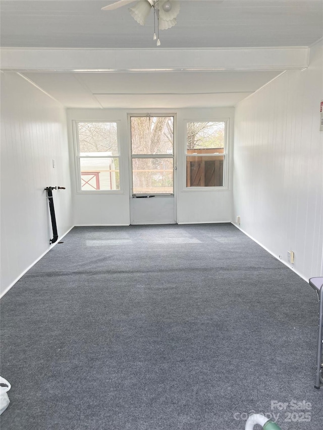 unfurnished room with beamed ceiling and carpet flooring