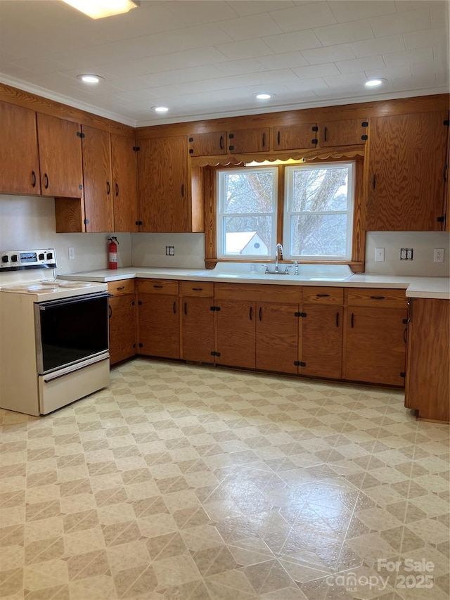 kitchen with light floors, white electric stove, light countertops, and brown cabinets