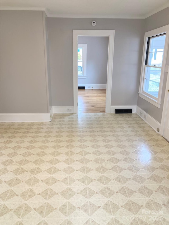 unfurnished room featuring baseboards, visible vents, light floors, and ornamental molding