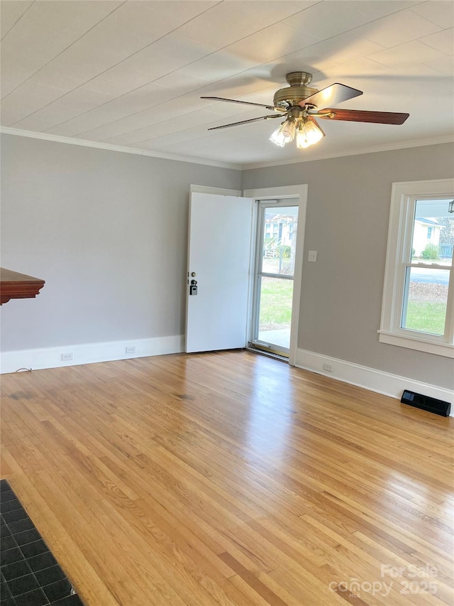 unfurnished living room featuring light wood-type flooring, visible vents, a ceiling fan, crown molding, and baseboards