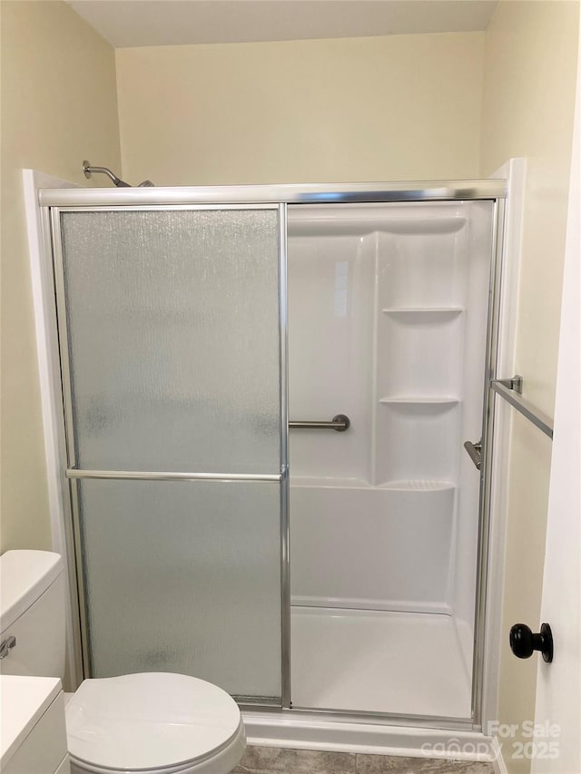 bathroom featuring toilet and a stall shower