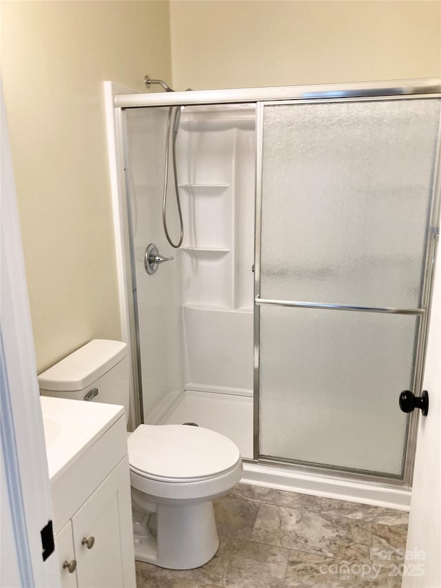 full bathroom featuring a shower stall, toilet, and vanity