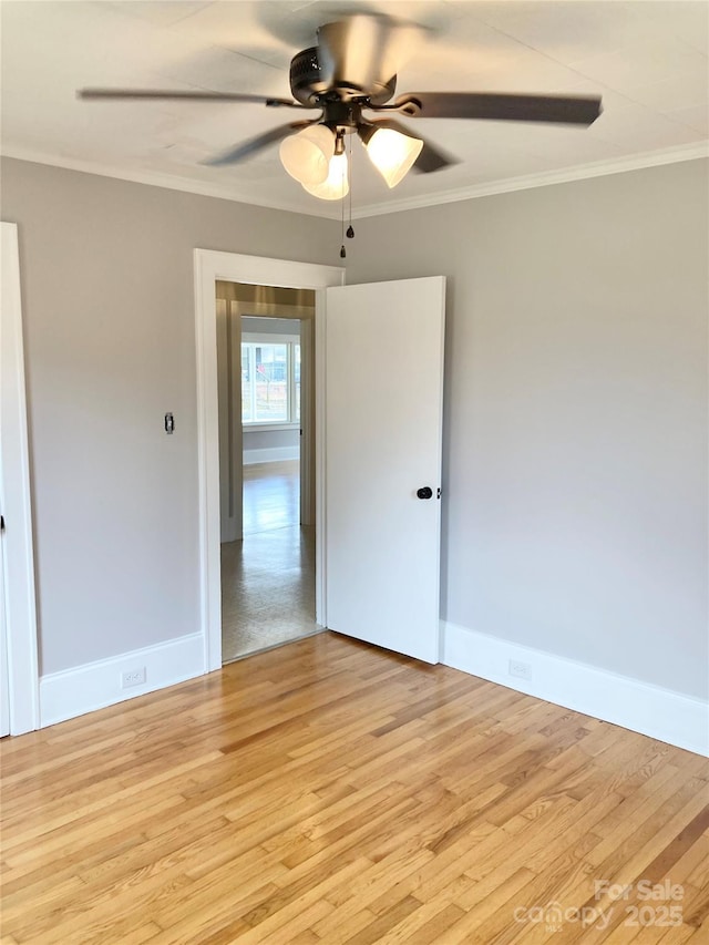 spare room with ceiling fan, light wood-type flooring, baseboards, and ornamental molding