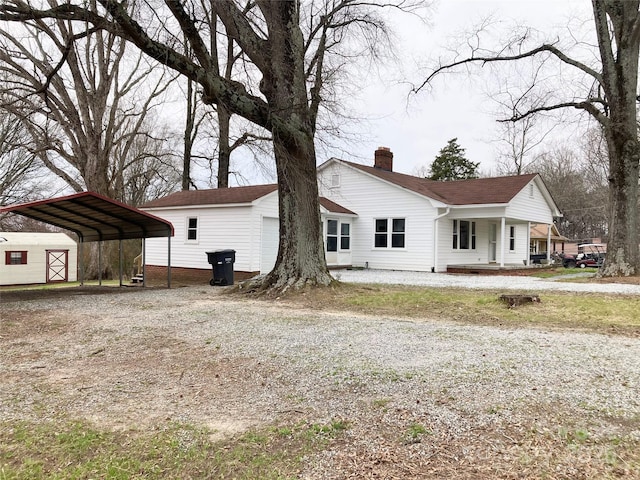 exterior space featuring a carport, a chimney, covered porch, and driveway