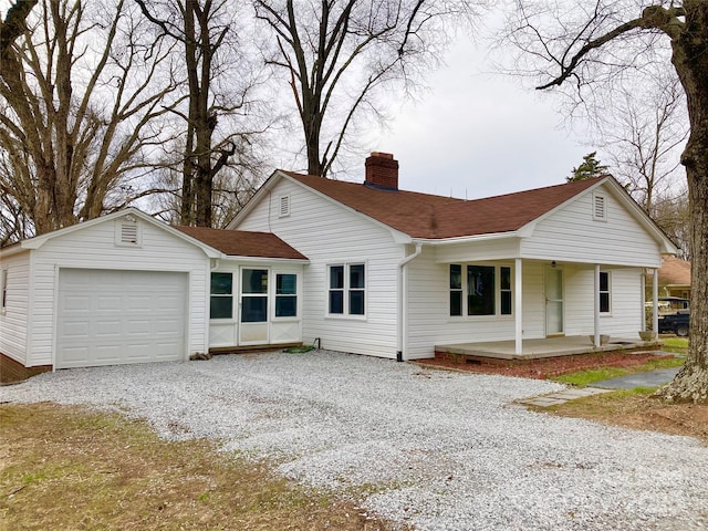 view of front facade featuring an attached garage, gravel driveway, a chimney, and a shingled roof