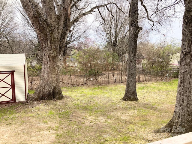 view of yard featuring an outbuilding, a storage shed, and fence