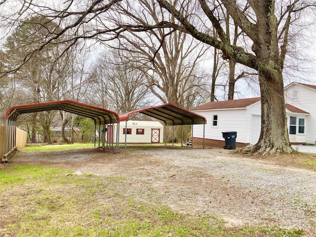 view of yard featuring an outbuilding, a carport, driveway, and fence