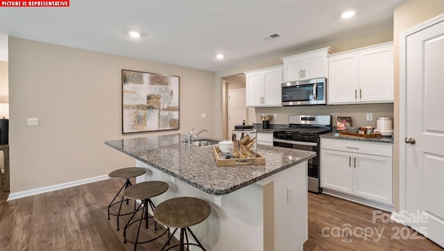 kitchen featuring visible vents, a kitchen bar, dark wood-type flooring, a sink, and appliances with stainless steel finishes