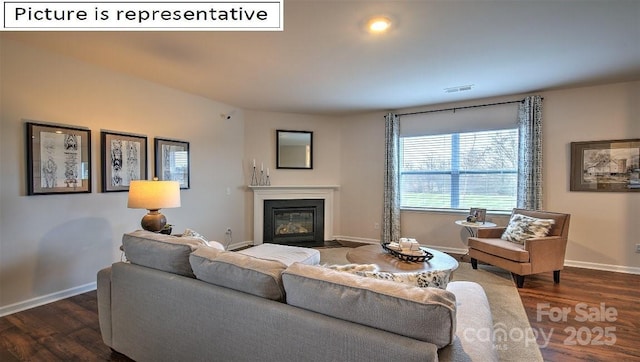 living room featuring visible vents, baseboards, dark wood-type flooring, and a fireplace with flush hearth