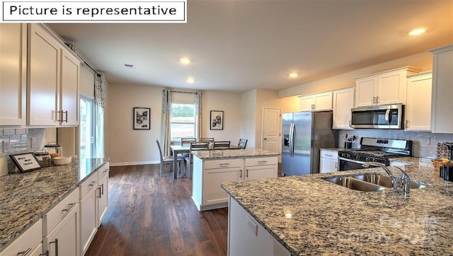 kitchen featuring light stone counters, backsplash, appliances with stainless steel finishes, and a sink