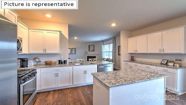 kitchen with stainless steel appliances, a peninsula, white cabinets, and dark wood finished floors