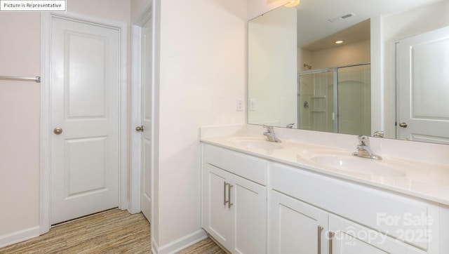 bathroom featuring a sink, visible vents, wood finished floors, and a stall shower