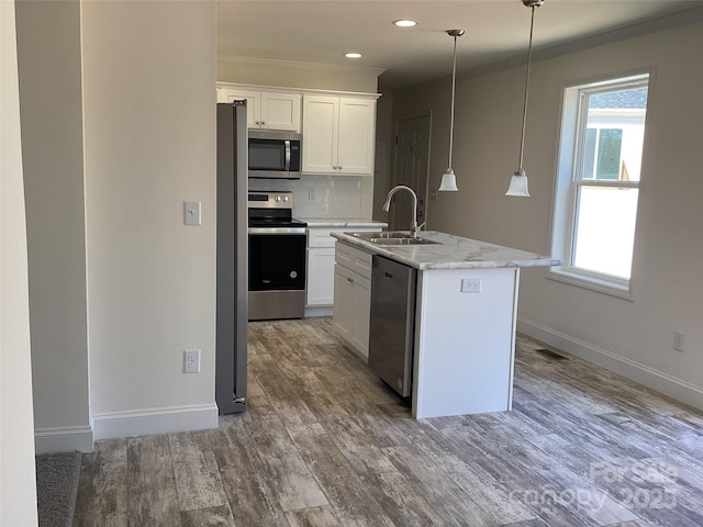 kitchen with wood finished floors, visible vents, a sink, decorative backsplash, and appliances with stainless steel finishes