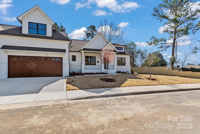 modern farmhouse featuring driveway, roof with shingles, and fence