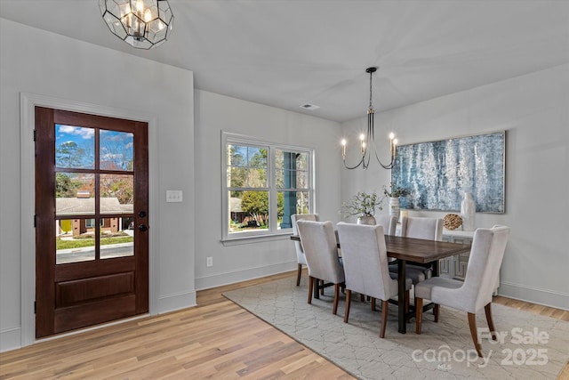 dining space featuring an inviting chandelier, light wood-style floors, and baseboards