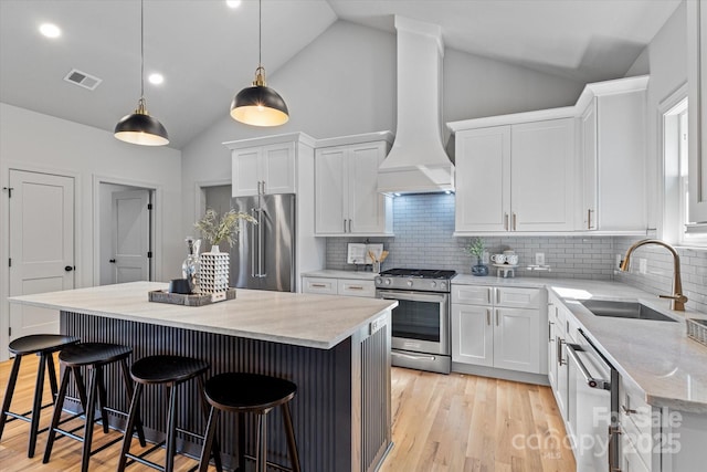 kitchen with visible vents, a sink, stainless steel appliances, custom range hood, and white cabinetry