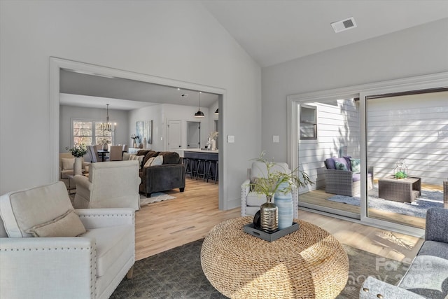 living room with visible vents, a notable chandelier, wood finished floors, and high vaulted ceiling