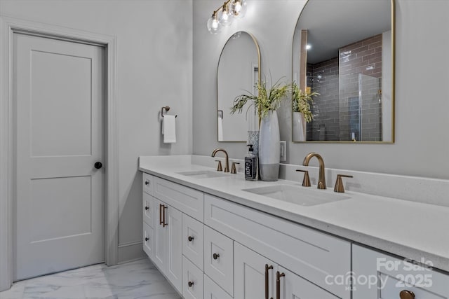 full bath featuring a sink, tiled shower, marble finish floor, and double vanity