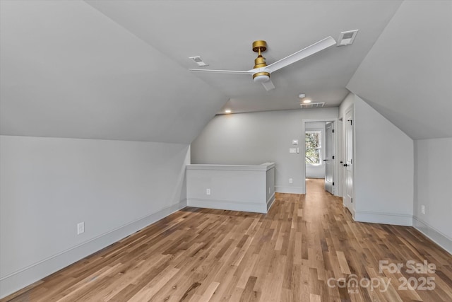 additional living space featuring visible vents, wood finished floors, baseboards, ceiling fan, and vaulted ceiling