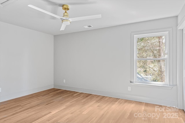 unfurnished room with a wealth of natural light, baseboards, light wood-style flooring, and a ceiling fan