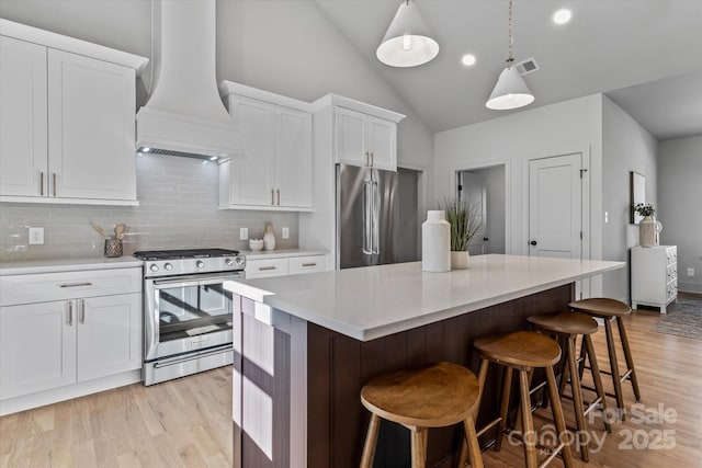 kitchen featuring visible vents, custom exhaust hood, stainless steel appliances, a kitchen island, and lofted ceiling