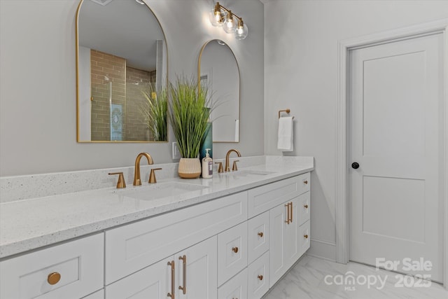 full bathroom with marble finish floor, a sink, double vanity, and a tile shower