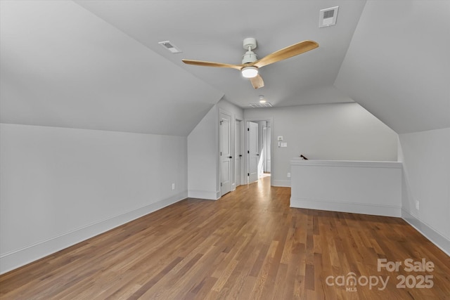 additional living space featuring vaulted ceiling, a ceiling fan, wood finished floors, baseboards, and visible vents
