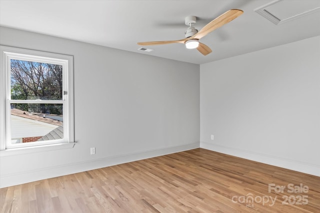 spare room featuring attic access, baseboards, visible vents, a ceiling fan, and wood finished floors