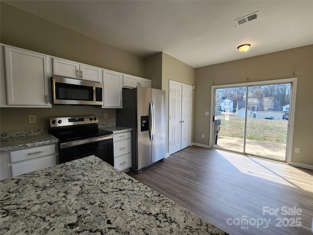 kitchen featuring dark wood-style floors, light stone countertops, appliances with stainless steel finishes, and white cabinets