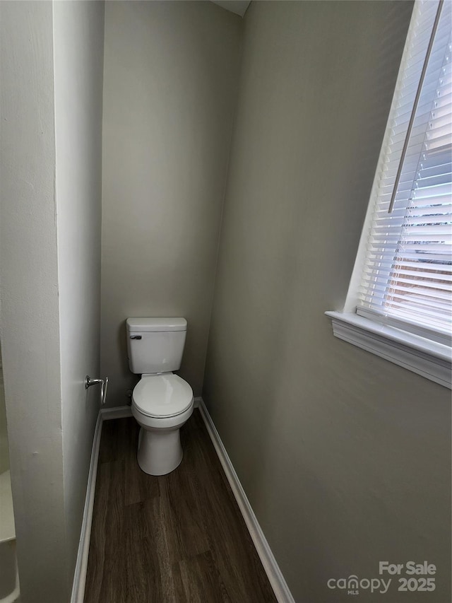 bathroom with toilet, baseboards, and wood finished floors