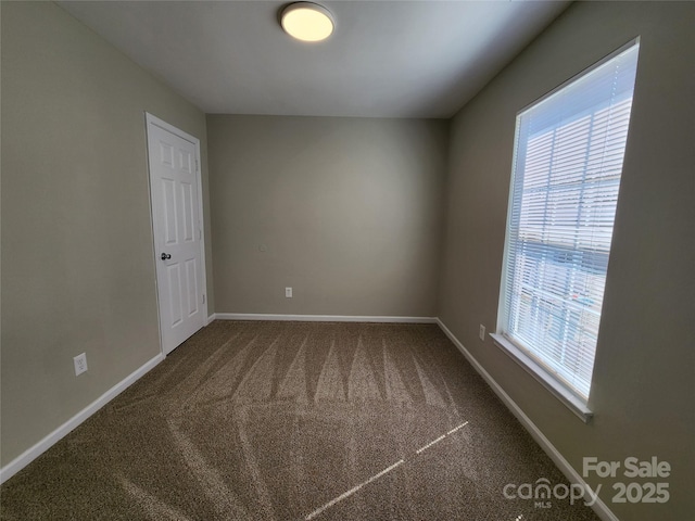 carpeted spare room featuring baseboards