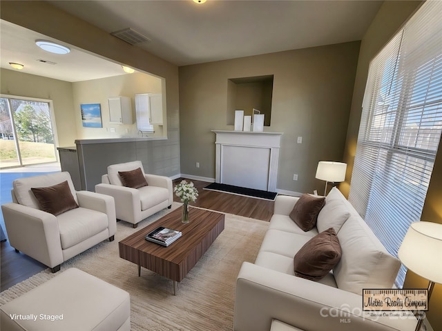 living area featuring visible vents, baseboards, and light wood finished floors