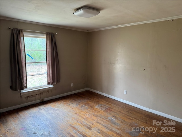 unfurnished room featuring hardwood / wood-style floors, crown molding, and baseboards