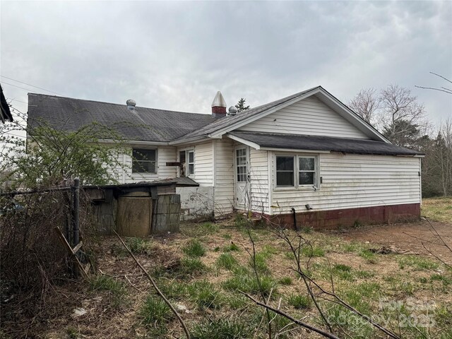 rear view of property with a chimney and fence