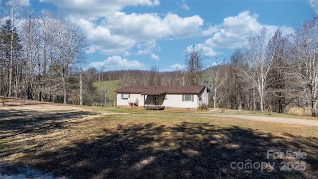 exterior space featuring crawl space, a forest view, and a front yard