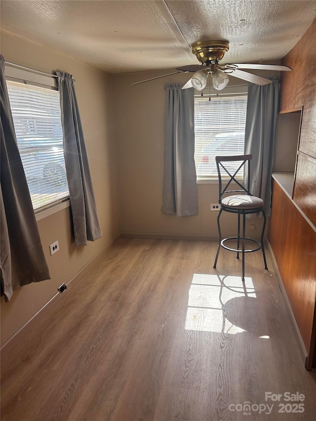 interior space with a textured ceiling, ceiling fan, and wood finished floors