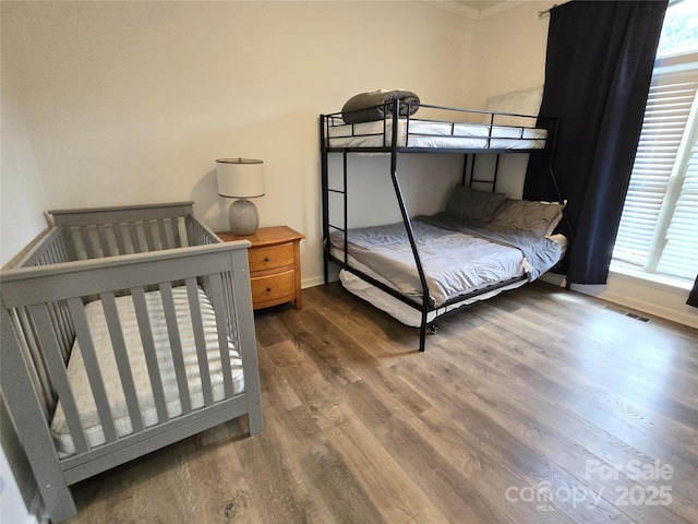 bedroom with visible vents, multiple windows, baseboards, and wood finished floors