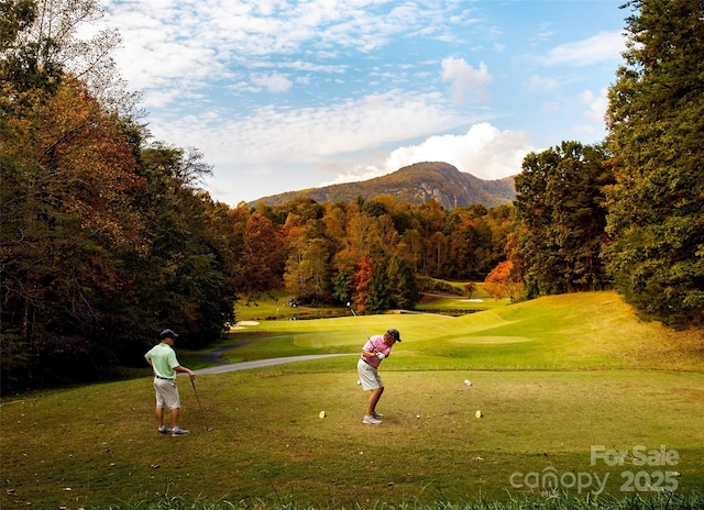 surrounding community featuring golf course view, a lawn, a mountain view, and a forest view