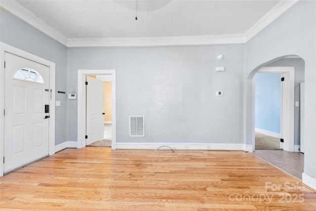 entryway with light wood-type flooring, visible vents, arched walkways, and ornamental molding