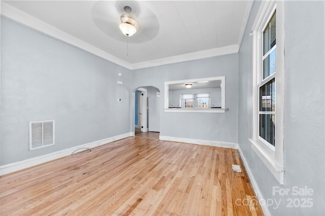 unfurnished living room featuring ornamental molding, arched walkways, visible vents, and ceiling fan