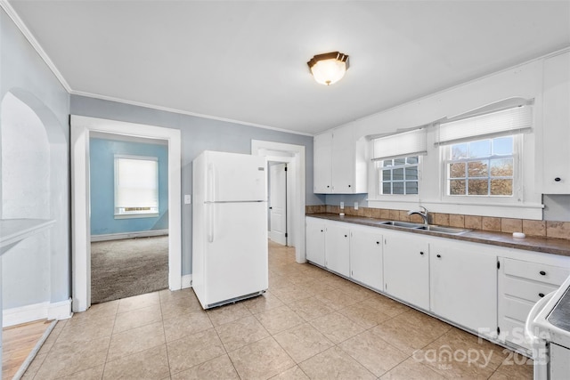 kitchen featuring freestanding refrigerator, a sink, white cabinetry, dark countertops, and a wealth of natural light