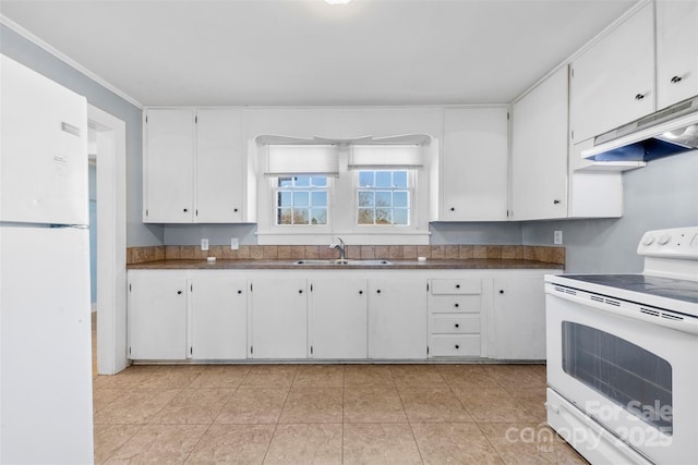 kitchen featuring dark countertops, under cabinet range hood, white cabinets, white appliances, and a sink