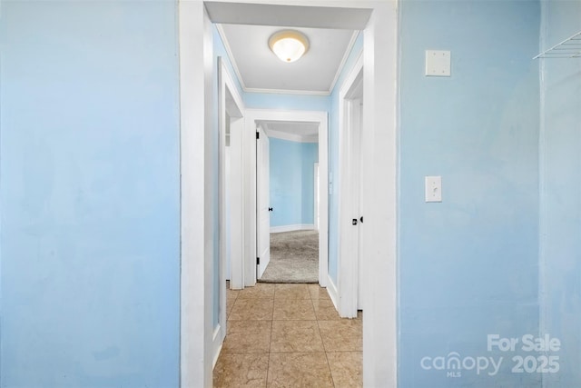 hall featuring light tile patterned floors, baseboards, and ornamental molding