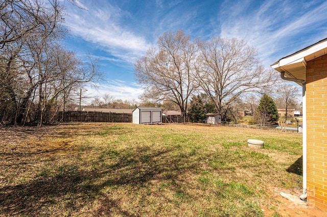 view of yard with an outdoor structure, fence, and a storage shed
