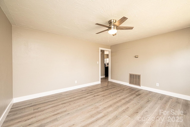 unfurnished room with a textured ceiling, baseboards, visible vents, light wood-style floors, and ceiling fan