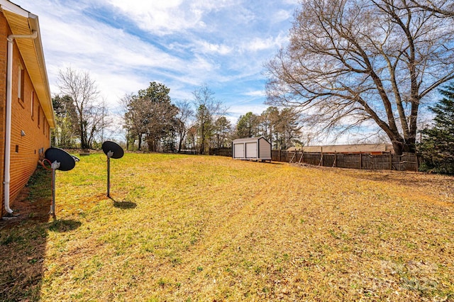 view of yard featuring an outdoor structure, fence, and a storage shed